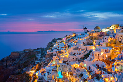 Oia met traditionele witte huizen en windmolens op het eiland Santorini, Griekenland in het blauwe avonduur